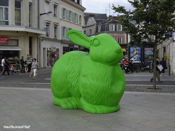 A large green plastic bunny statue in a city square