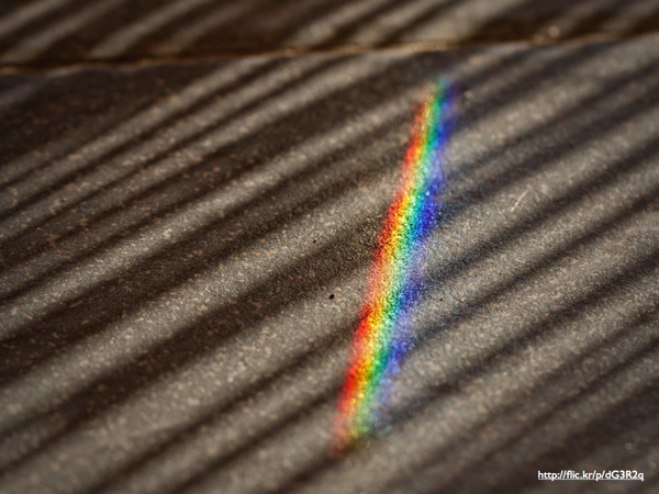 A rainbow cast from a prism on a sidewalk