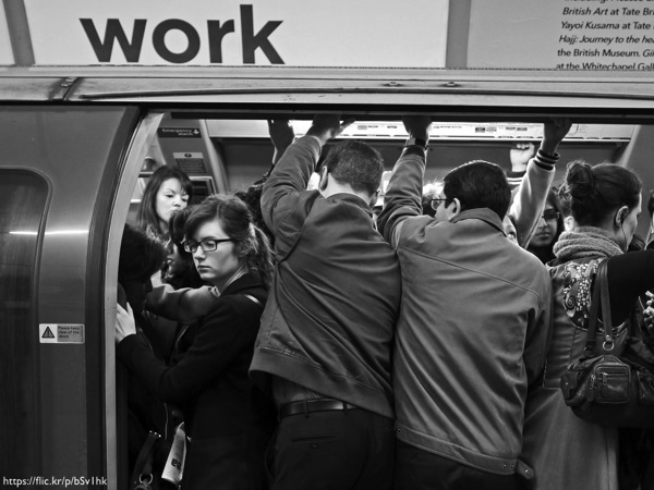 A crowded subway car with the word 'Work' written above it