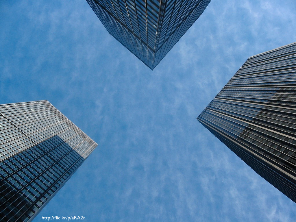 A photograph of three skyscrapers from the perspective of someone standing on the ground and looking up at them.